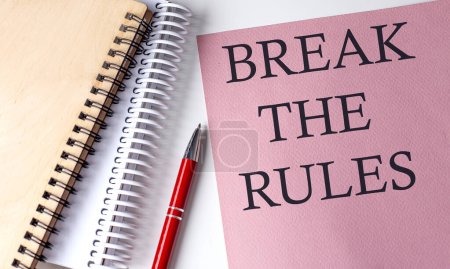 BREAK THE RULES Wort auf rosa Papier mit Bürogeräten auf weißem Hintergrund