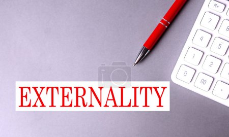 EXTERNALITY text written on gray background with pen and calculator