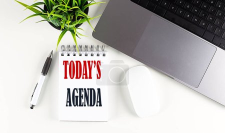 TODAY S AGENDA text written on a notebook with laptop and mouse , white background