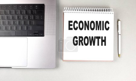 ECONOMIC GROWTH text on a notebook with laptop and pen . 