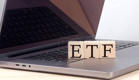 ETF-Wort auf einem Holzklotz am Laptop, Geschäftskonzept