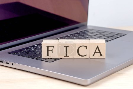 FICA-Wort auf dem Holzklotz am Laptop, Geschäftskonzept