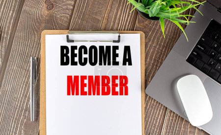 BECOME A MEMBER text on a clipboard paper with laptop, mouse and pen . 
