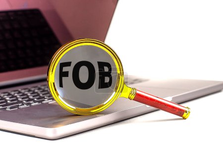 FOB-Wort auf Lupe am Laptop, weißer Hintergrund . 