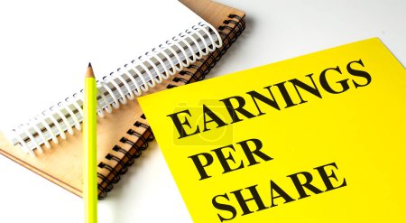 EARNINGS PER SHARE text on a yellow paper with notebooks. 
