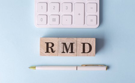RMD word on wooden block with pen and calculator on a blue background . 