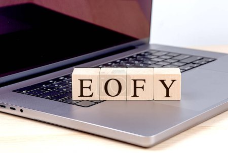 EOFY palabra en un bloque de madera en el ordenador portátil, concepto de negocio. 