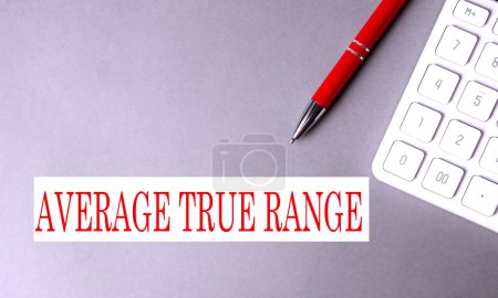 AVERAGE TRUE RANGE Text auf grauem Hintergrund mit Stift und Taschenrechner. 