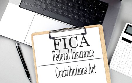 FICA word on clipboard on a laptop with calculator and pen . 