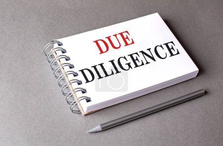 DUE DILIGENCE text on a notebook on grey background . 