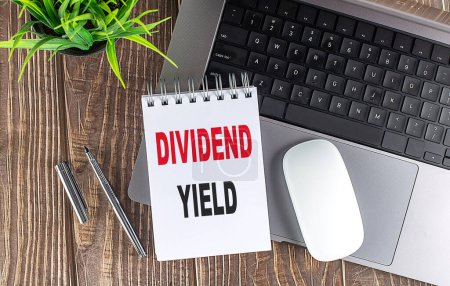 DIVIDEND YIELD text on a notebook with laptop, mouse and pen 