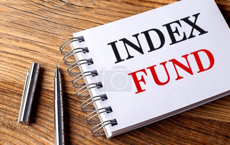 INDEX FUND text on a notebook with pen on the wooden background . 