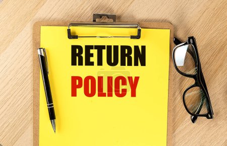 Photo for RETURN POLICY text on a yellow paper on clipboard with pen and glasses. - Royalty Free Image