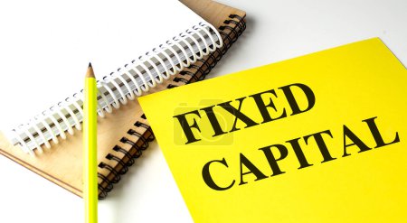 FIXED CAPITAL text on a yellow paper with notebooks. 