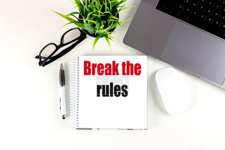 BREAK THE RULES text on a notebook with laptop, mouse and pen . 