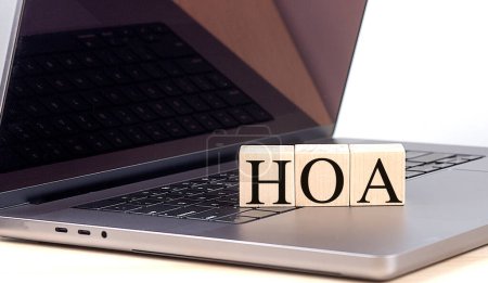 HOA word on a wooden block on laptop , business concept. 