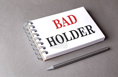BAD HOLDER text on a notebook on grey background 