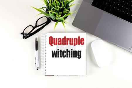 QUADRUPLE WITCHING text on a notebook with laptop, mouse and pen . 
