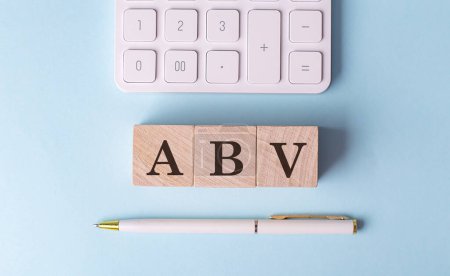 ABV-Wort auf Holzblock mit Stift und Taschenrechner auf blauem Hintergrund . 
