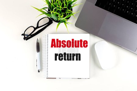 ABSOLUTE RETURN text on a notebook with laptop, mouse and pen . 