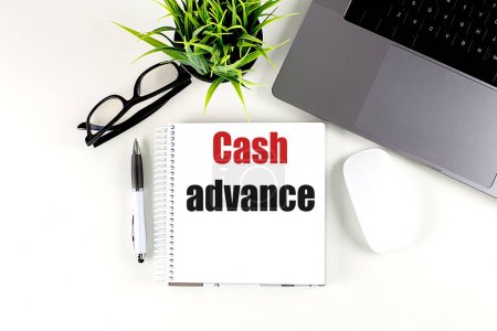 CASH ADVANCE text on a notebook with laptop, mouse and pen . 