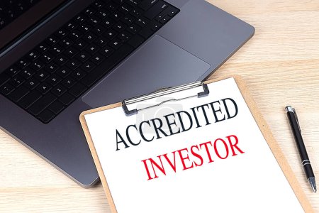 Photo for ACCREDITED INVESTOR text on a clipboard on laptop. - Royalty Free Image