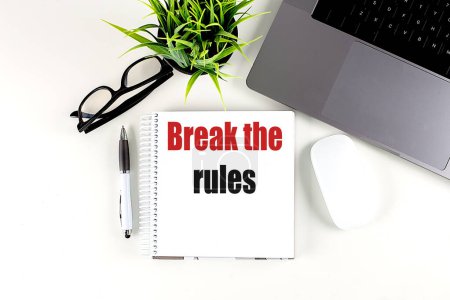 BREAK THE RULES text on a notebook with laptop, mouse and pen . 