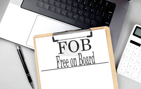 FOB- KOSTENLOSE ON BOARD Wort auf einem Clipboard auf dem Laptop mit Taschenrechner und Stift . 