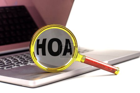 HOA word on magnifier on a laptop , white background . 