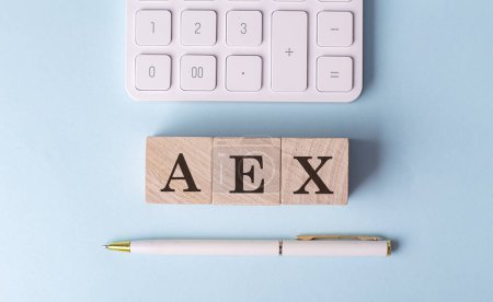 AEX word on wooden block with pen and calculator on a blue background . 