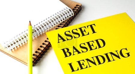 ASSET BASED LENDING text on a yellow paper with notebooks. 