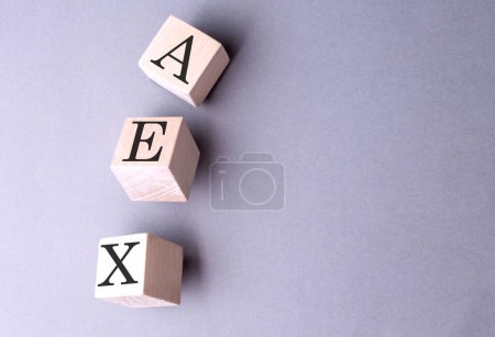 AEX word on a wooden block on gray background 