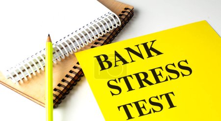BANK STRESS TEST Text auf gelbem Papier mit Notizbüchern. 
