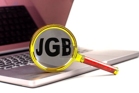JGB word on a magnifier on laptop , white background . 