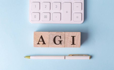 AGI-Wort auf Holzblock mit Stift und Taschenrechner auf blauem Hintergrund . 