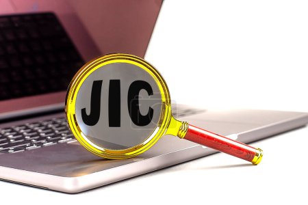 JIC-Wort auf Lupe am Laptop, weißer Hintergrund . 