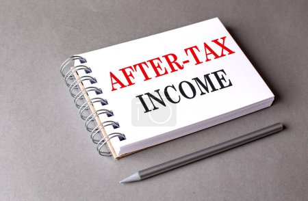 AFTER-TAX INCOME text on a notebook on grey background 