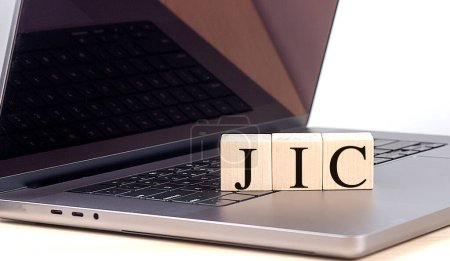 JIC mot sur bloc de bois sur un ordinateur portable, concept d'entreprise.