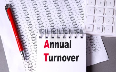 ANNUAL TURNOVER text on a notebook with chart , pen and calculator. 