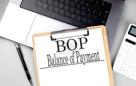 BOP- BALANCE OF PAYMENT word on clipboard on a laptop with calculator and pen . 