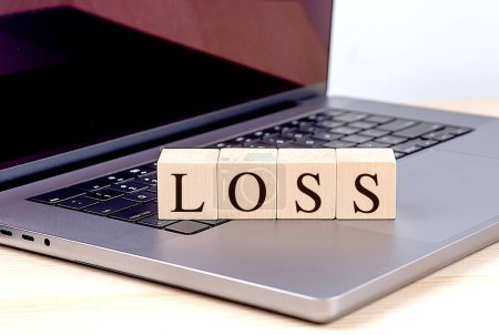 LOSS word on wooden block on a laptop , business concept. 