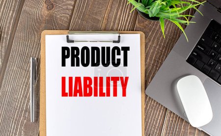 PRODUCT LIABILITY text on a clipboard paper with laptop, mouse and pen . 