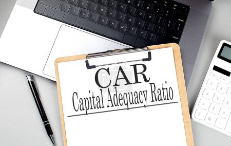 CAR - CAPITAL ADEQUACY RATIO word on clipboard on a laptop with calculator and pen . 