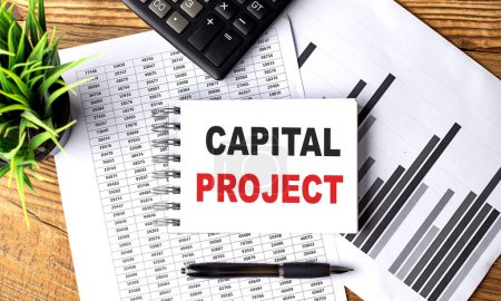 CAPITAL PROJECT text on a notebook on chart with calculator and pen . 
