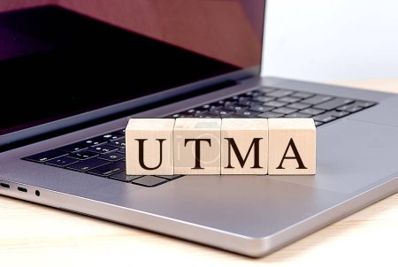 Téléchargez les photos : Mot UTMA sur un bloc de bois sur un ordinateur portable, concept d'entreprise. - en image libre de droit