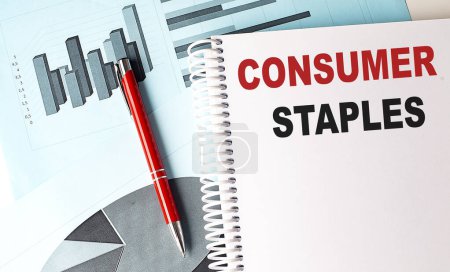 CONSUMER STAPLES text on a notebook on chart background . 