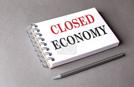 CLOSED ECONOMY text on a notebook on grey background 