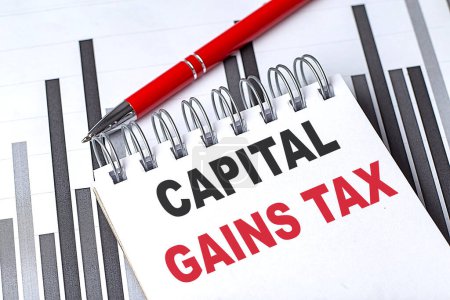 CAPITAL GAINS TAX text on a notebook on chart with pen .