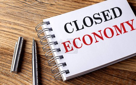 CLOSED ECONOMY text on a notebook on grey background 