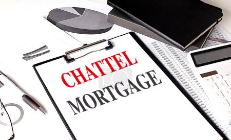 CHATTEL MORTGAGE text on a clipboard on chart with notebook and calculator. 